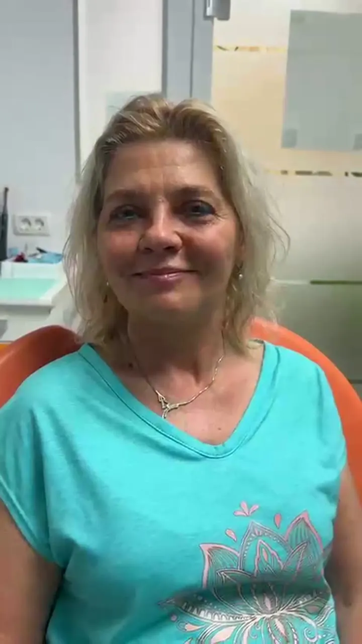 Pacientă a clinicii Atelierul de Zâmbete Colordent, în scaunul stomatologic, după inserarea implanturilor la mandibulă